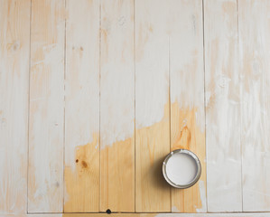 Open cans of paint on a wooden background. Partially painted with white