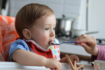 Little baby feeding with a spoon