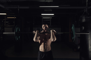 Fototapeta na wymiar The clean and jerk exercise - young man doing weightlifting workout at the gym.
