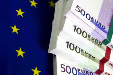 Bundles of euro bills. Two five hundred euro bundles and two hundred euro bundles. The Flag of Europe as background. Yellow stars circle. Close up image.