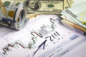 Concept of currency trading. Hundred us dollar bills lying . Bundle of euro hundred bills. Currency us euro rate chart under the bills. Rolled us dollar bills.Handmade marks on the currency chart.
