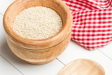 Quinoa natural en cuenco de madera sobre una mesa blanca. Vista superior