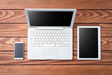 Overhead shot of white digital devices on wooden table