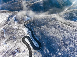 Fototapeten Winding road in the middle of the winter in a high mountain pass © Calin Stan