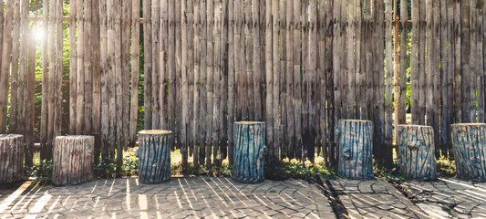 Vintage tone picture of garden furniture made from wooden log on dry bamboo wall background