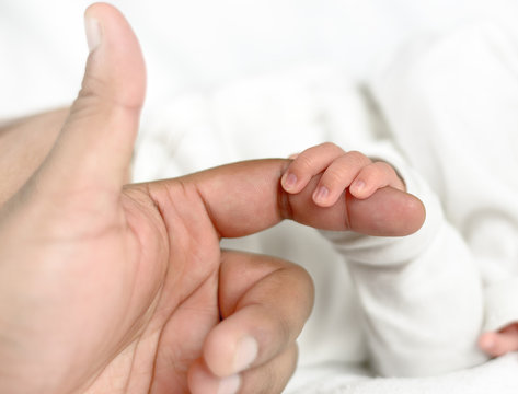 Neugeborenes hält den Finger seiner Mutter
