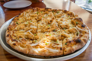 Fresh pizza with chicken and garlic sauce on wooden table