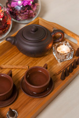 Traditional Asian ceramic teapot and cups on wooden table decoration with flowers and candles