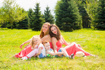 Fototapeta premium Happy family. Young mothers and kids boy and girl on sunny day. Portrait moms and children on nature. Positive human emotions, feelings, joy.