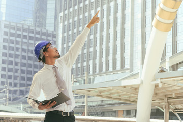 architect in blue helmet, pointing at building under constructio