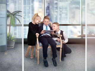 Fototapeta premium Children in the office with a tablet and phone to discuss business ideas. The concept of early adulthood, teamwork, office staff