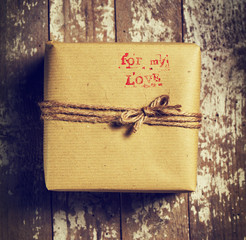 Vintage gift with natural rope in craft paper on a wooden backgr