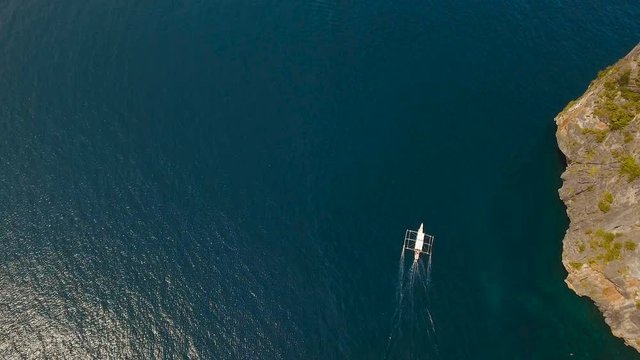 Aerial view of motor boat in sea. Aerial image of motorboat floating in a turquoise blue sea water. Sea landscape with wake of small fast motorboat. Tropical landscape. Philippines, El Nido. 4K video