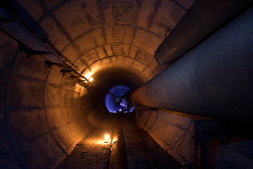 Round underground tunnel of heating duct with rusty tubes