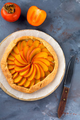 Persimmon galette, pie, tart on a gray stone background. Top view. Selective focus.