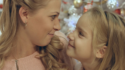 Daughter with mother near the decorated Christmas tree