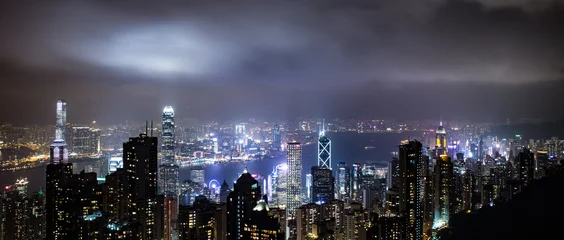 Zelfklevend Fotobehang Hong Kong, China skyline panorama from across Victoria Harbor. Hong Kong city skyline view from harbor with skyscrapers buildings reflect in water at sunset © JONGSUN BAEK