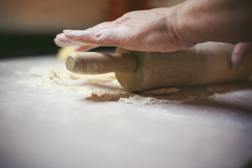 hand modeling dumplings at home in the kitchen. rolling pin in hand rolls dough