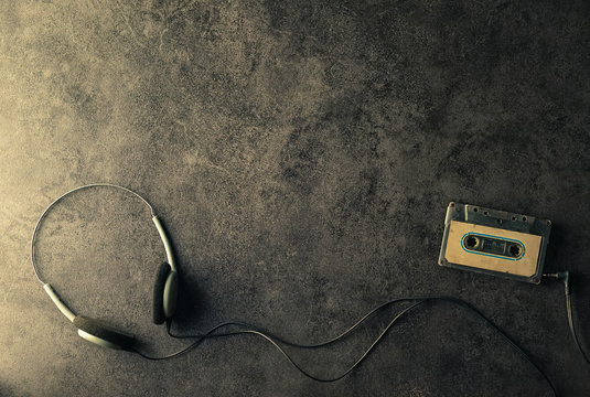 Earphone and Old cassette tape on dark background in vintage color style

