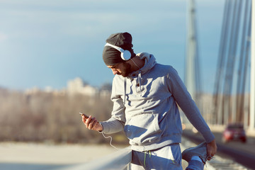 Fototapeta premium Man runner stretching legs before exercise run outdoors. Urban modern lifestyle healthy living concept.
