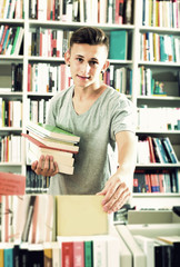 Positive teenager boy looking for new book on shelves