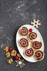 Obraz na płótnie Canvas Cranberry nut swirl cookies on a white oval dish New Year's treats with nuts, cranberries, fir branches. Top view