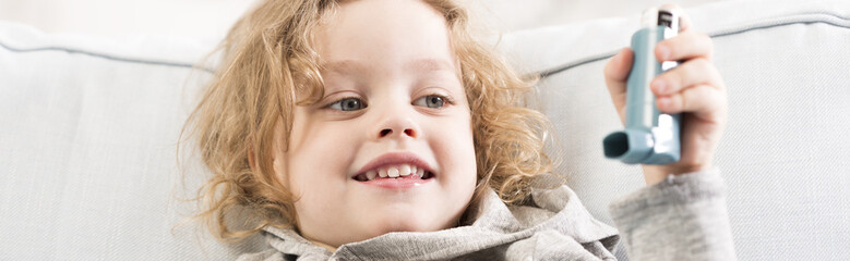 Smiling little boy holding inhaler