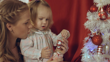 Mum with a small daughter decorate a Christmas tree