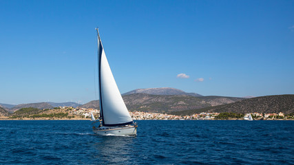 Naklejka na ściany i meble Sailboat with white sails in the Aegean sea near Greece coasts. Sailing, luxury yachts.