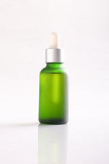 Green essential oil bottle on white background.