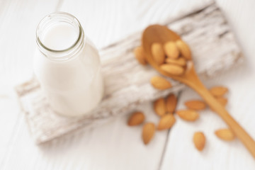Almond milk in a glass bottle and almond nuts on a stand