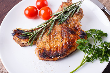 Grilled rib steak with rosemary and tomatoes on white dish