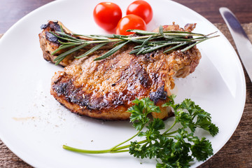 Grilled rib steak with rosemary and tomatoes on white dish