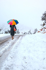 Colorful umbrella holding by young girl who is walking in winter nature