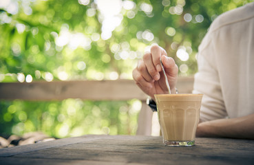 People hand stirred coffee in the cup on the wooden table
