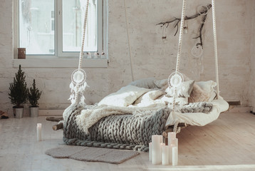 The bed suspended from the ceiling. Grey big cozy blanket knit. Scandinavian style, gray plaid,...