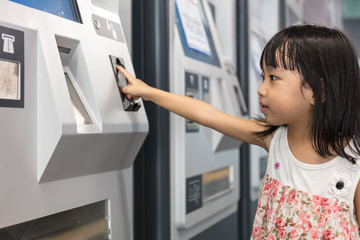 Fototapeta na wymiar Asian Chinese little girl buying admission ticket at MRT station