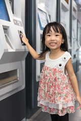 Fototapeta na wymiar Asian Chinese little girl buying admission ticket at MRT station