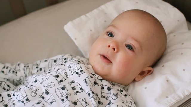 A cute little baby is happy smiling lying in a bed