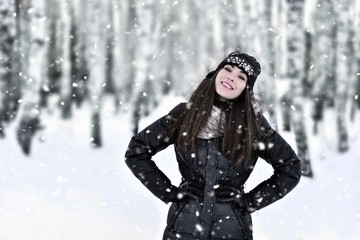 Fototapeta na wymiar Girl with dark long hair in the winter park in snowfall