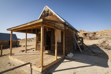 Abandoned ghost town home or shack in the Nevada Desert under clear blue skies.
