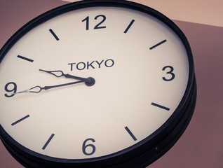 An airport clock showing Tokyo time zone at 9 past 45, Retro filter color