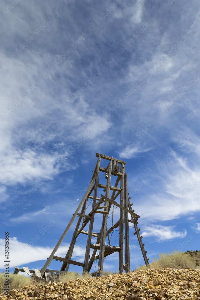 Wall mural old mining head frame in the nevada desert under blue sky with clouds.