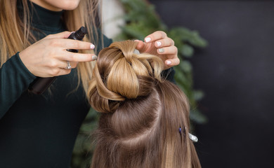 Hairdresser makes upper bun hairstyle close-up on brunette hair