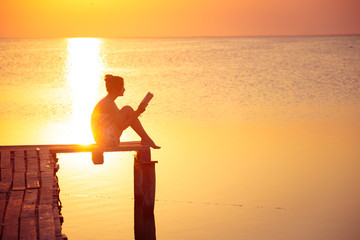 Obraz premium Dziewczyna czytająca na czas zachodu słońca