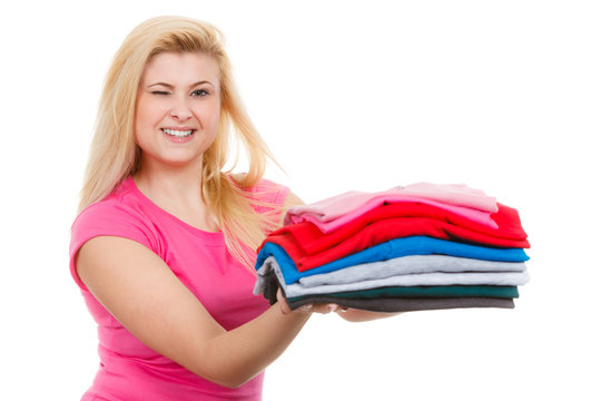 Happy woman holding pile of folded clothes