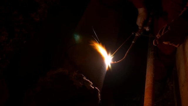 A person welding two heating pipes together at night during an urgent intervention...