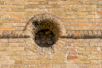 Ancient brick wall with round embrasure in Popov Castle located in town of Vasylivka, Ukraine