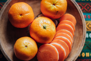 Tangerines and carrot on an earthen plate on a bright turkish tablecloth.
