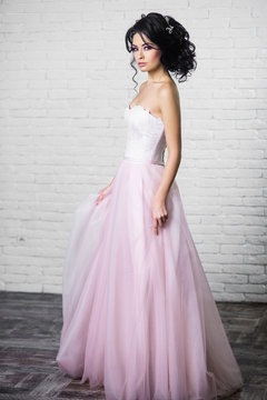 beautiful young brunette woman in a light pink long dress